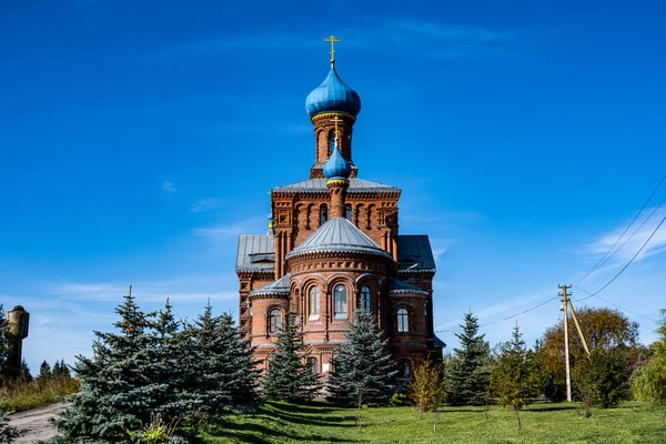 森の近くの丘の上の青い空の上の古い赤レンガ造りの教会 — ストック写真