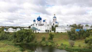 Mavi kubbeli eski beyaz taş manastırın panoramik bir görüntüsü. İHA 'dan çekilen yeşil ağaçların arka planında.