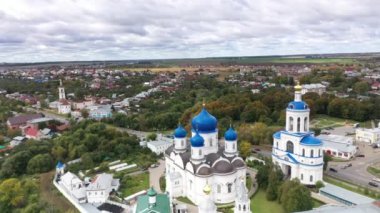 Mavi kubbeli eski beyaz taş manastırın panoramik bir görüntüsü. İHA 'dan çekilen yeşil ağaçların arka planında.