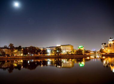 Şafak vakti büyük bir metropolün nehir kenarına parlayan fenerlerin yansımasıyla.
