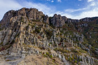Gökyüzünün arka planında sıradışı çıkıntıları ve hikayeleri olan güzel dağlar ve bir drondan çekilen vadi.