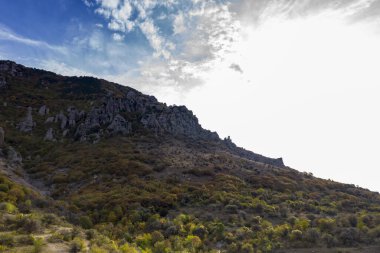 Gökyüzünün arka planında sıradışı çıkıntıları ve hikayeleri olan güzel dağlar ve bir drondan çekilen vadi.