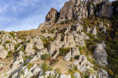 Gökyüzünün arka planında sıradışı çıkıntıları ve hikayeleri olan güzel dağlar ve bir drondan çekilen vadi.