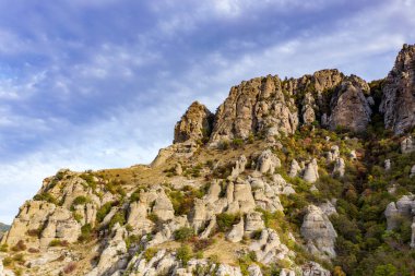 Gökyüzünün arka planında sıradışı çıkıntıları ve hikayeleri olan güzel dağlar ve bir drondan çekilen vadi.