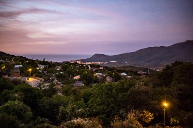 Dağların ve vadinin panoramik manzarasına karşı yeşil çam ağaçları ve sonbahar gökyüzü