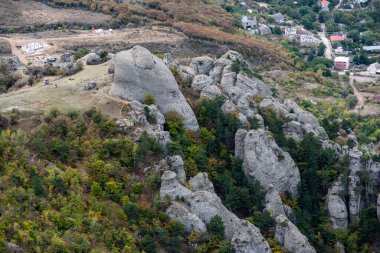 Dağların ve vadinin panoramik manzarasına karşı yeşil çam ağaçları ve sonbahar gökyüzü