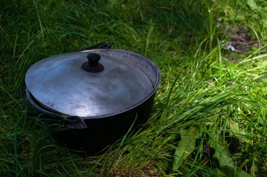 Çimlerin üzerinde büyük bir kazan. Ormanda yemek hazırlığı.