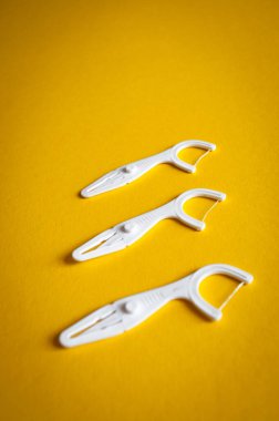 Sarı arka planda üç diş plastik kürdanı (diş ipi). 