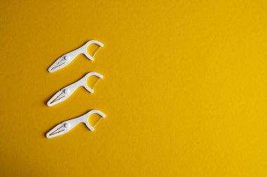 Sarı arka planda üç diş plastik kürdanı (diş ipi). 