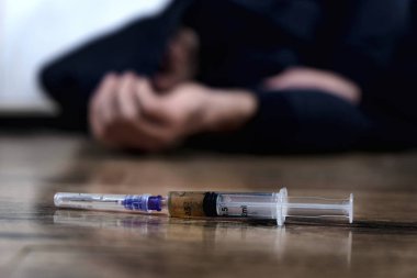 Elini seçici odak yakınındaki bir şırınga ile aşırı dozda uyuşturucu bağımlısı zemin üzerinde yatıyordu.