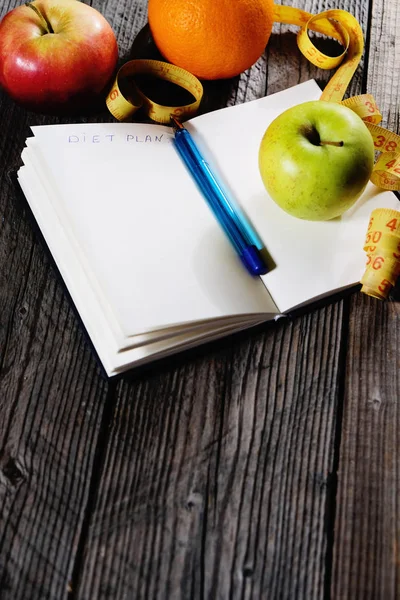 Healthy fruit with notebook for planing in diet concept and weight loss on wooden background copyspace
