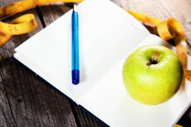 Bir diyet planlama. Bir not defteri c bir yazıt - diyet, bir ölçüm bandı, bir elma ve kalem, portre.