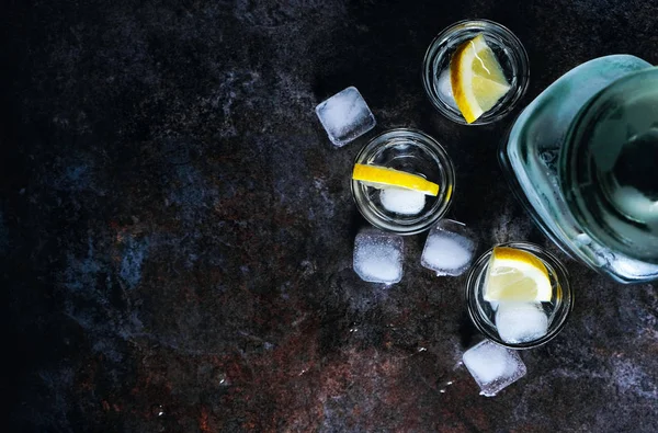 Vodka em copos com limão e gelo. Na mesa de pedra preta. Espaço de cópia . — Fotografia de Stock