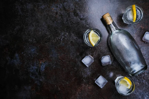 Vodka froide dans des verres avec du citron sur fond de pierre. Vue du dessus, espace de copie . — Photo