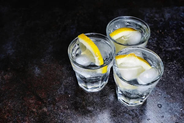 Джин-тоник с лимоном и льдом на деревянном столе — стоковое фото