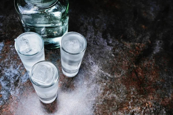 Vodka. Tiros, copos com vodka com gelo .Dark pedra background.Copy espaço .Selective foco — Fotografia de Stock