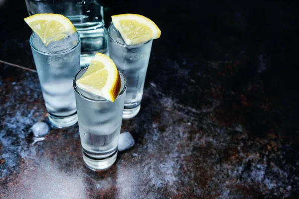 Vodka. Tiros, copos com vodka com gelo .Dark pedra background.Copy espaço .Selective foco Imagem De Stock