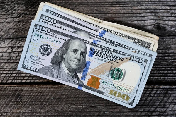Egy halom száz dolláros bankjegy a fa asztalon. — Stock Fotó