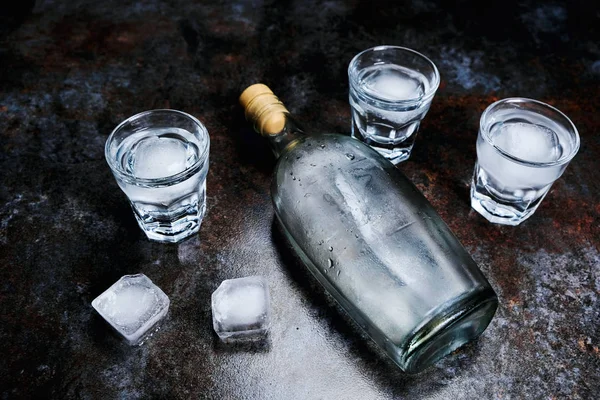 Bouteille de vodka avec verres et glace. Sur fond de pierre . — Photo