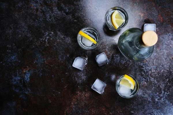 Vodka fria em copos de tiro com limão em fundo de pedra. Vista superior, espaço de cópia . — Fotografia de Stock
