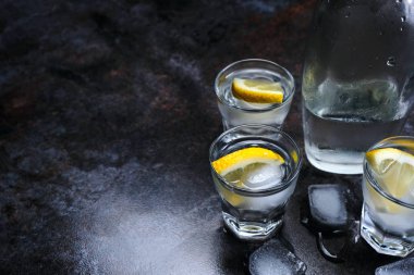 Votka. Atış, gözlük ile votka ve limonlu buzlu. Taş koyu arka plan.