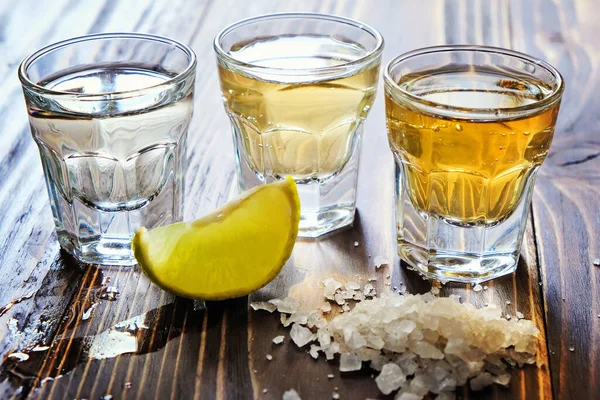 Tequila mexicaine or et argent et sel de citron vert sur fond de bois — Photo