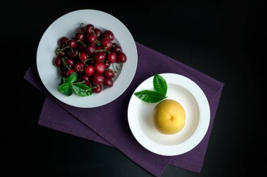 Şeftali ve kiraz beyaz bir yemek tabağında.