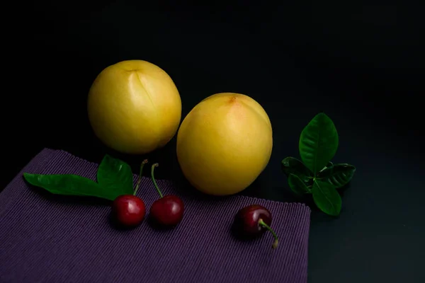 Two Yellow Peaches Cherries Purple Table Cloth — Stock Photo, Image