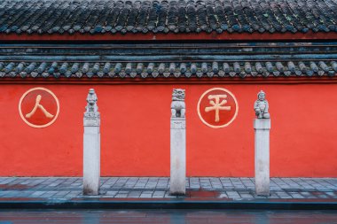 Kırmızı Duvar Taşı Maymunu, Taş Aslan Asker Heykeli Wenshu Manastırı, Chengdu, Sichuan, Çin. Kırmızı duvardaki altın kelime çevirisi: insanlar, barış
