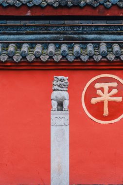 Wenshu Manastırı, Chengdu, Sichuan, Çin 'de arka plan olarak kırmızı duvarı olan taş aslan heykeli. Kırmızı duvardaki altın kelime: