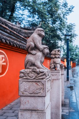 Wenshu Manastırı, Chengdu, Sichuan, Çin 'de arka plan olarak kırmızı duvarı olan taş aslan heykeli. Kırmızı duvardaki altın kelime:
