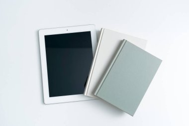 Beyaz bir masada iki kitap ve iPad.