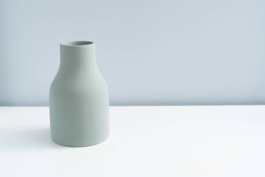 Minimalist bir evde gri-yeşil sade bir vazo. 