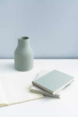 Masaya konulmuş minimalist defter ve vazo. Açık-beyaz premium mobilyalar 