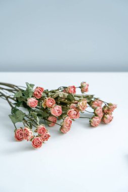 Beyaz masada pembe hava kurutulmuş güller.