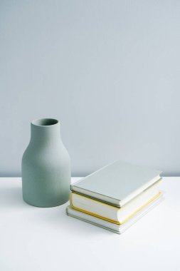 Masaya konulmuş minimalist defter ve vazo. Açık-beyaz premium mobilyalar 