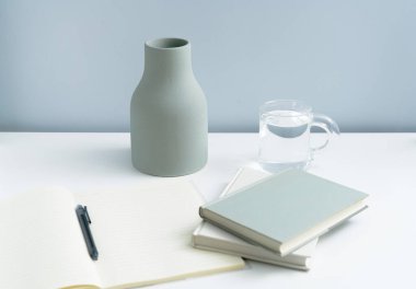 Masaya konulmuş minimalist defter ve vazo. Açık-beyaz premium mobilyalar 