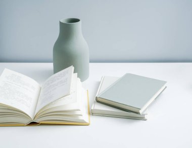 Masaya konulmuş minimalist defter ve vazo. Açık-beyaz premium mobilyalar 