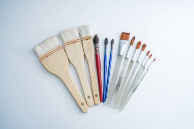 Beyaz masanın üzerinde bir sıra suluboya fırça. Ressam fırça aracı