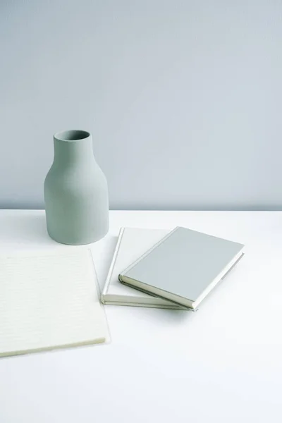 Masaya konulmuş minimalist defter ve vazo. Açık-beyaz premium mobilyalar 