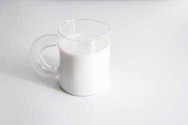 Şeffaf bir kupada süt. Beyaz arka planda bir bardak süt..