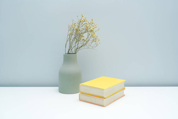 Vase and book notebook with dried flowers on the white desk