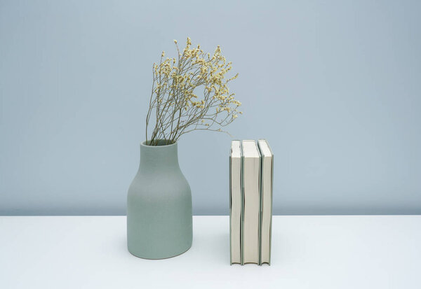 Vase and book notebook with dried flowers on the white desk