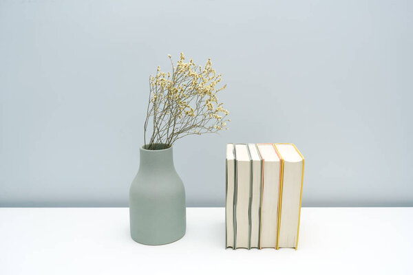 Ваза и тетрадь с сушеными цветами на белом столе
