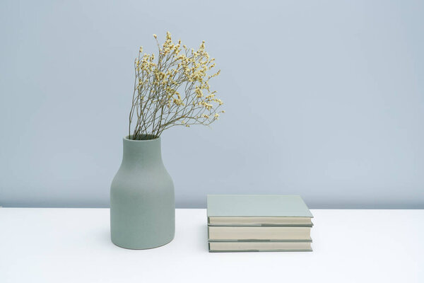 Vase and book notebook with dried flowers on the white desk