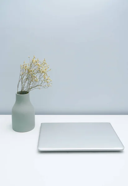 Vase and laptop on white desktop