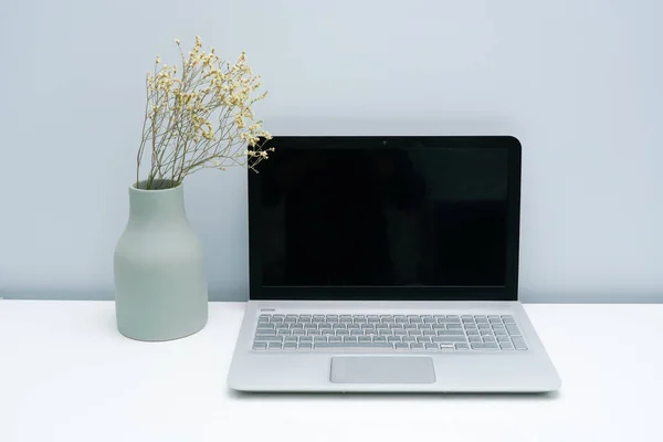 Vase and laptop on white desktop