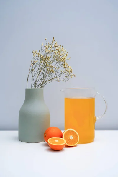 一只花瓶 上面放着干花和一杯橙汁 — 图库照片