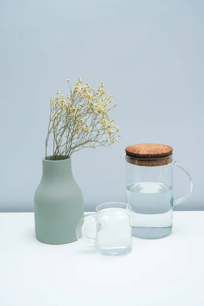 Vas Med Torkade Blommor Och Ett Glas Vatten Det Vita — Stockfoto
