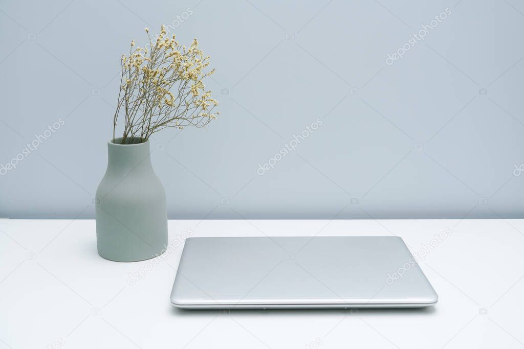 Vase and laptop on white desktop